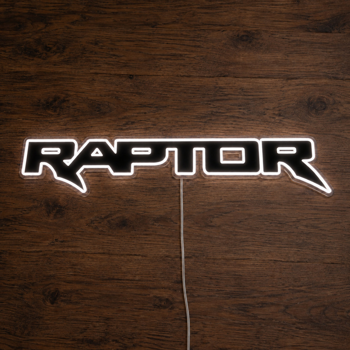 Ford Ranger Raptor LED Neon Sign in white, featuring outlined Raptor lettering on a wooden surface.