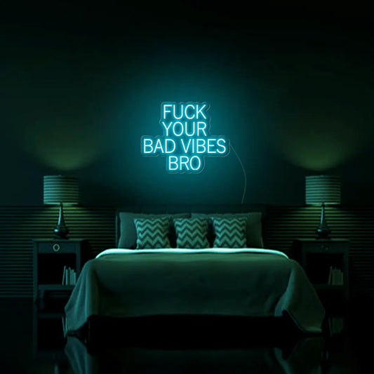 Fk Your Bad Vibes Bro LED Neon Sign in turquoise, featuring stacked block lettering on a dark bedroom wall above a bed.