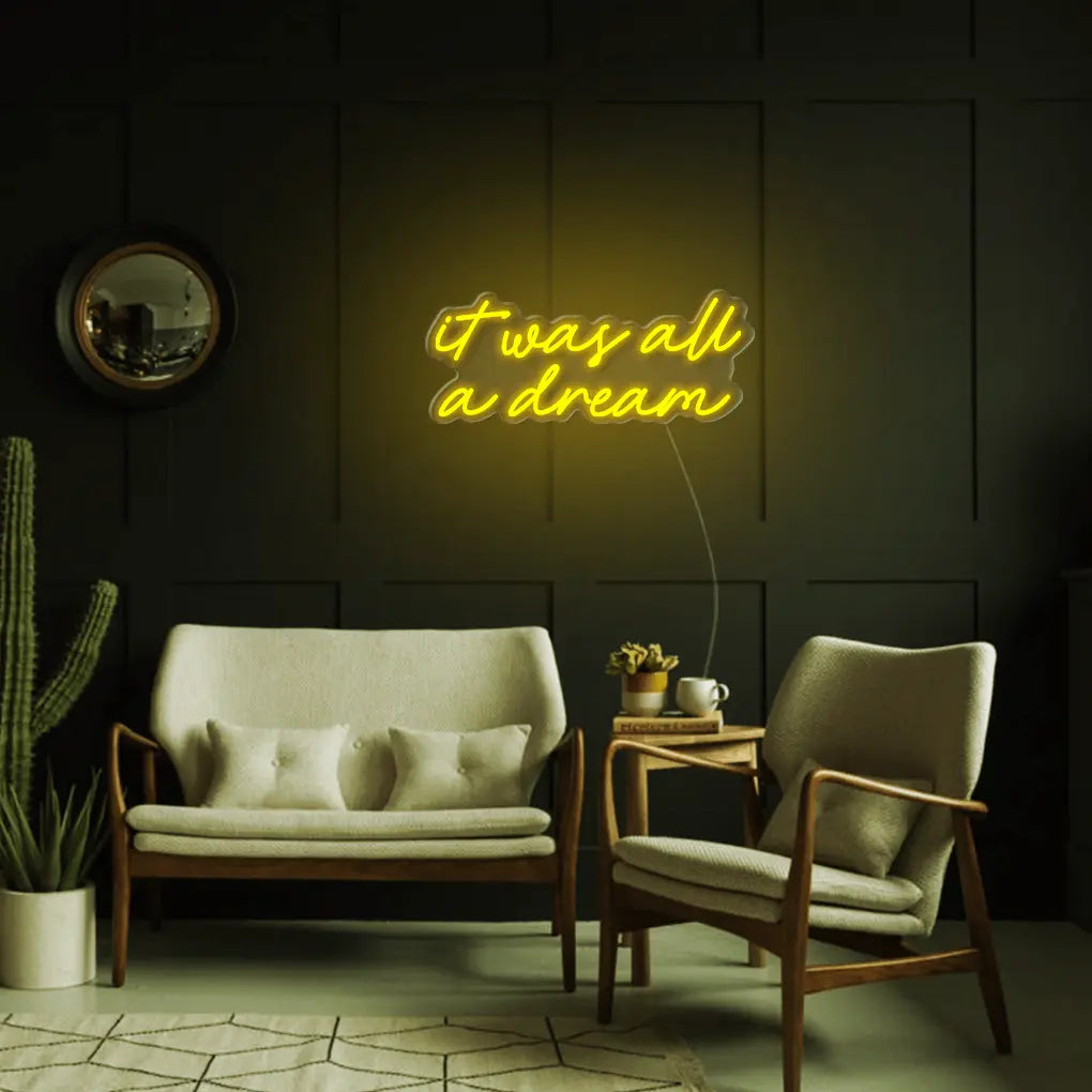 It Was All A Dream LED Neon Sign in yellow, featuring script lettering above a small sofa on a dark panelled wall.
