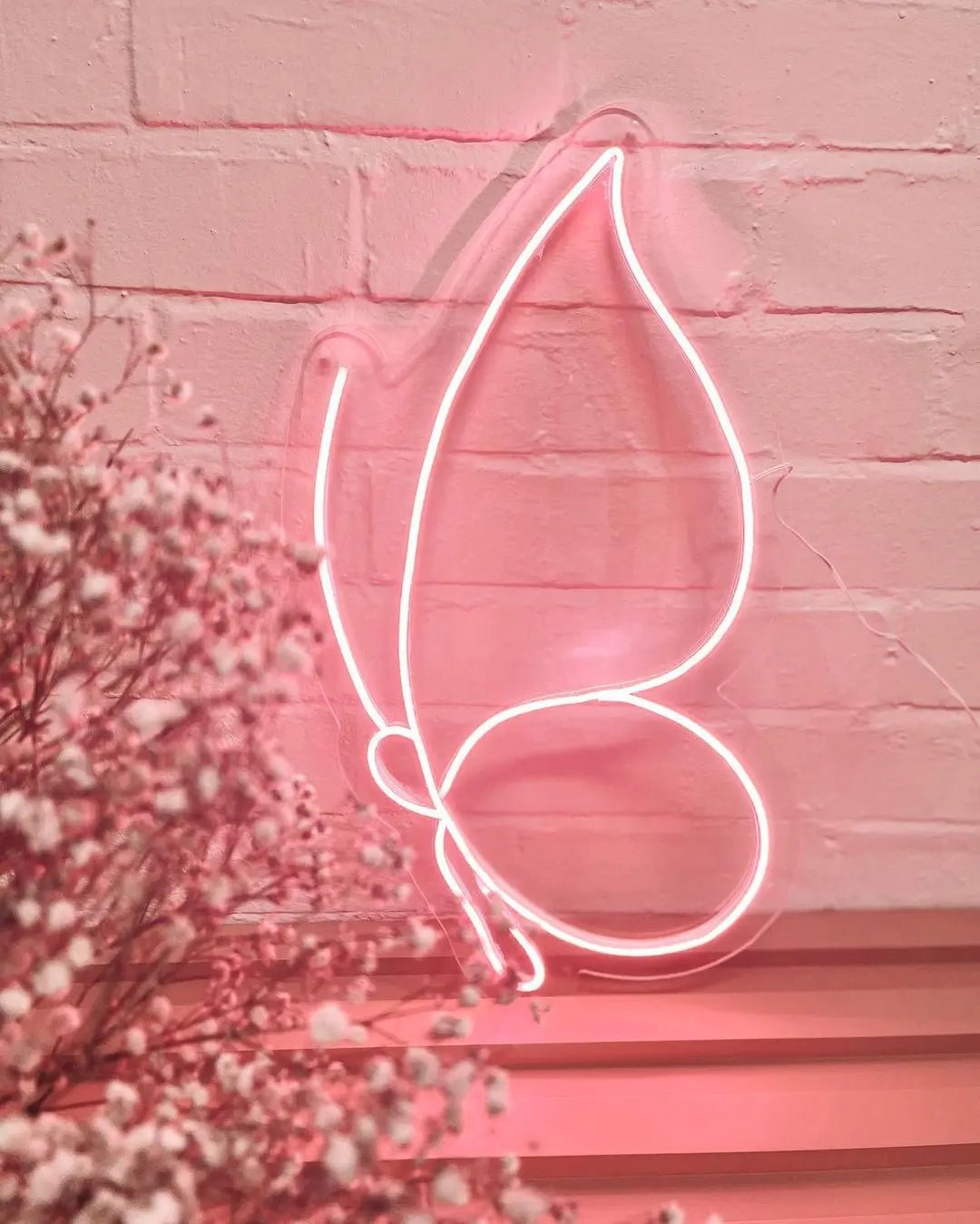 Butterfly LED Neon Light Sign in pink, featuring butterfly outline on a pink brick wall.