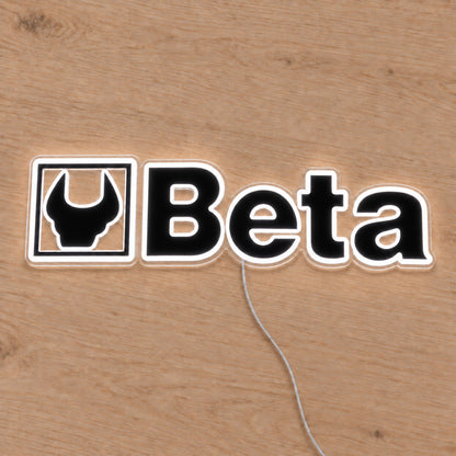 Beta LED Neon Sign, featuring illuminated vehicle logo on a wooden surface.