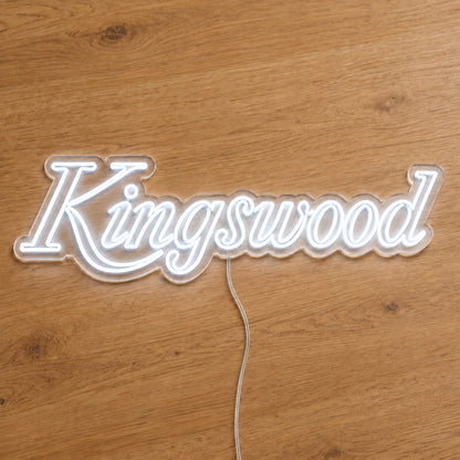 Holden Kingswood LED Neon Sign in white, featuring Kingswood script lettering on a wooden surface.