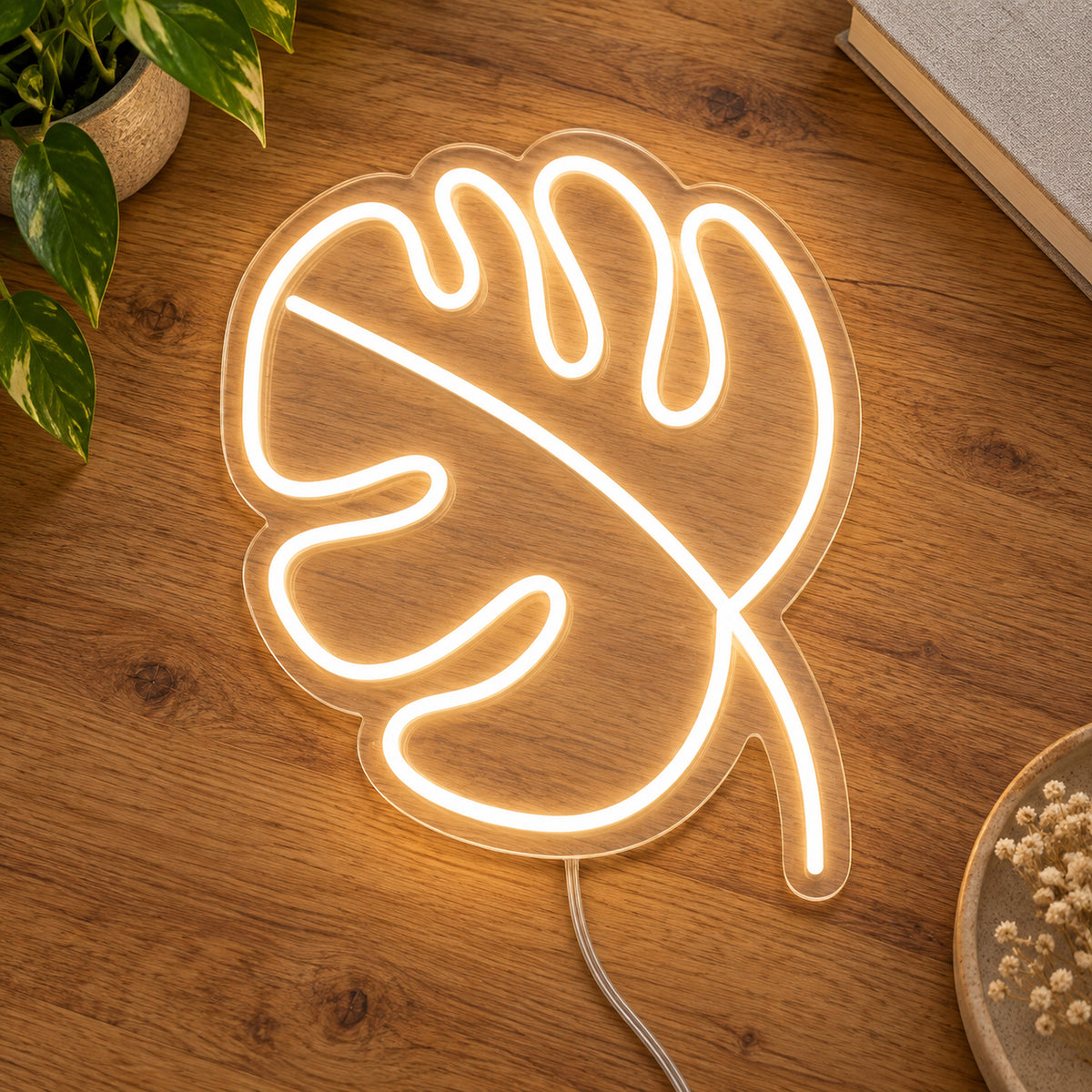 Leaf LED Neon Light Sign in warm white, featuring monstera-leaf outline on a wooden surface.