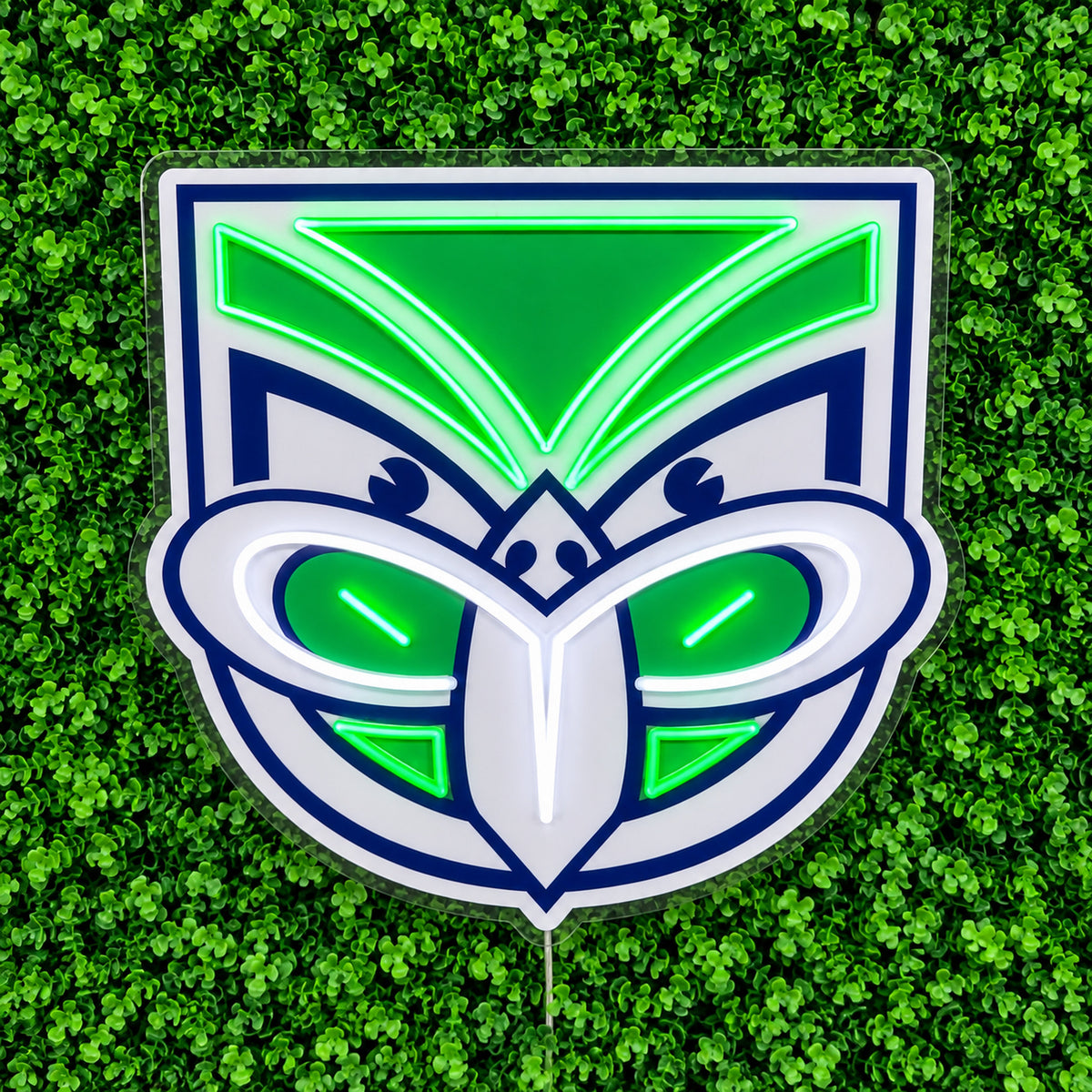New Zealand Warriors Neon Sign, featuring illuminated team logo on a green foliage wall.