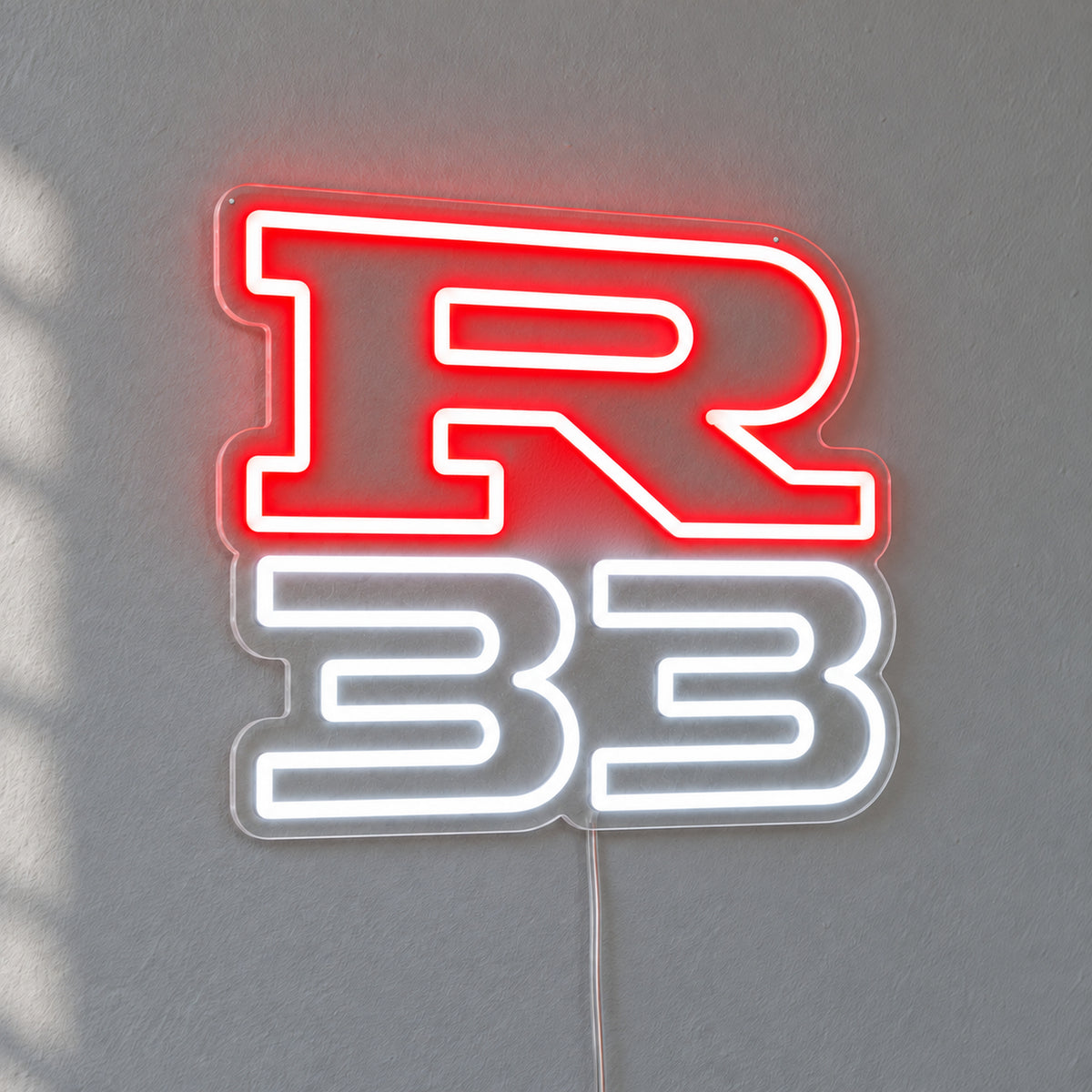 Nissan R33 LED Neon Sign in red and white, featuring R33 lettering on a grey wall.