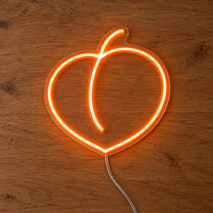 Peach LED Neon Light Sign in orange, featuring peach outline on a wooden surface.