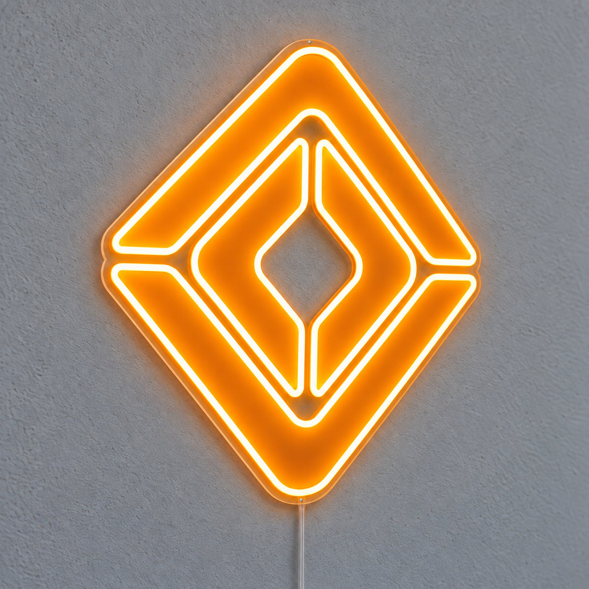 Renault neon sign with an orange diamond emblem on clear acrylic, illuminated against a grey wall.