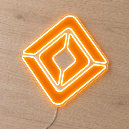 Renault neon sign with an orange diamond emblem on clear acrylic, shown at an angle on a wooden surface.