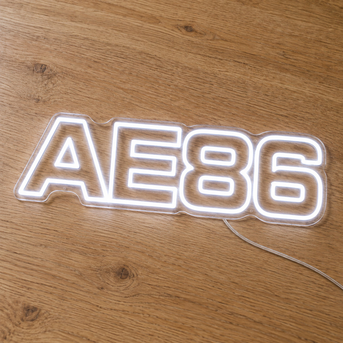 Toyota AE86 LED Neon Sign in white, featuring AE86 lettering on a wooden surface.