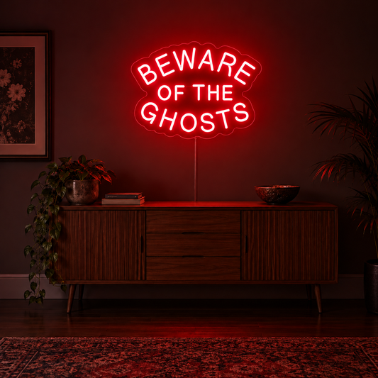 Beware of the Ghosts Neon Sign featuring Beware of the Ghosts wording arranged in curved red lettering, displayed on a dark wall above a wooden sideboard.
