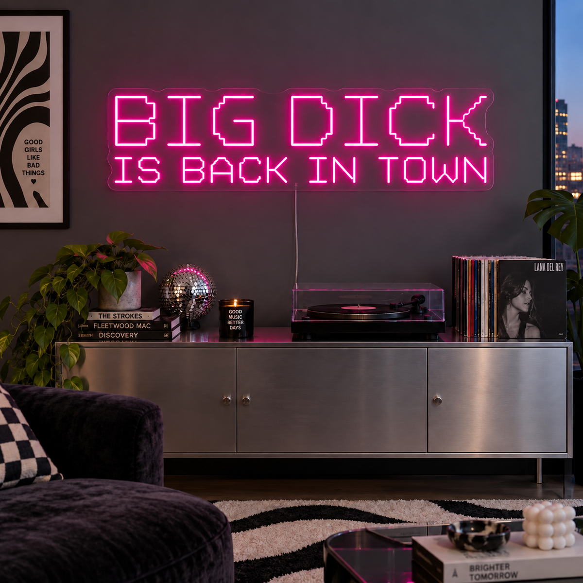 Big Dick Is Back In Town Neon Sign in pink above a record player and metal sideboard.