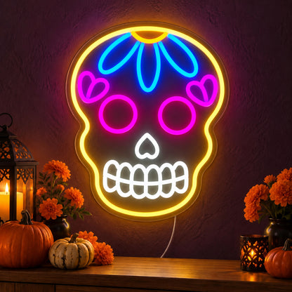 Colourful Sugar Skull Neon Sign featuring a yellow skull outline with pink eyes, a blue forehead flower and white teeth, glowing on a dark wall in a Halloween room display.