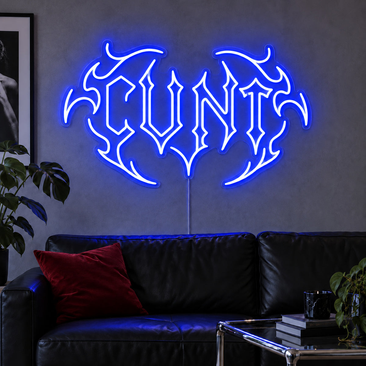 Cunt Neon Sign glowing blue in a tribal design above a black leather sofa.