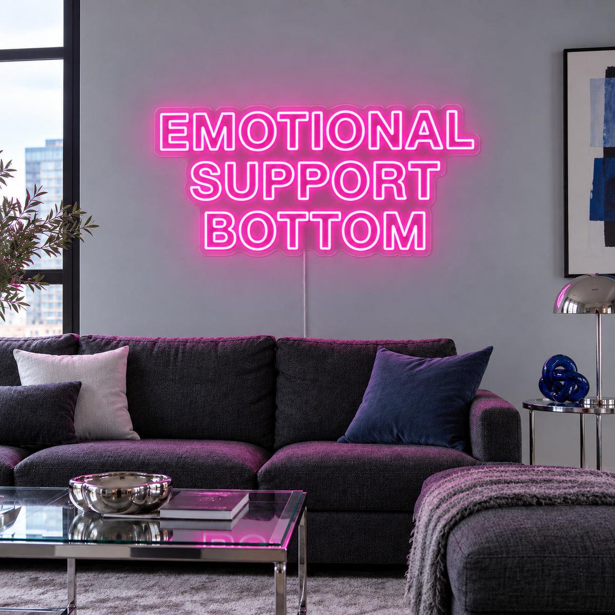 Rose Red version of the Emotional Support Bottom Neon Sign, shown above a charcoal sofa.