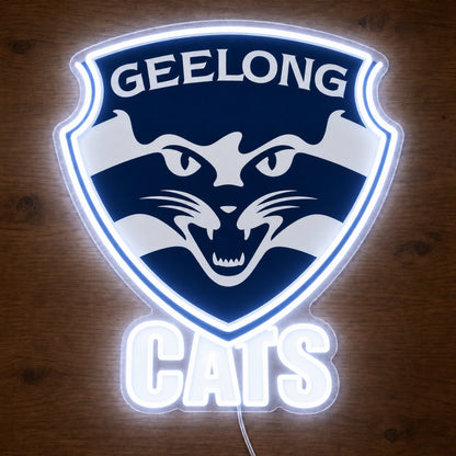 Geelong Cats neon sign glowing brightly on a wooden surface in dim lighting