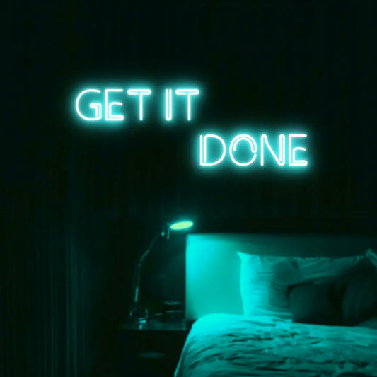Get It Done LED Neon Light Sign in turquoise, featuring two offset lines of block lettering illuminated above a bed.