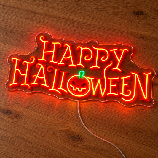 Happy Halloween Gothic Neon Sign featuring orange decorative Happy Halloween lettering with a pumpkin face and green stem, illuminated on clear acrylic lying on a natural oak wooden surface.