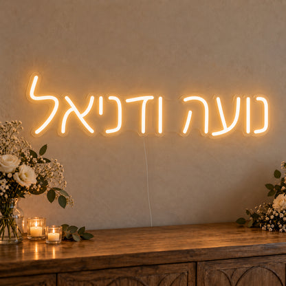 Personalised Hebrew Couple Names Neon Sign on clear cut-to-shape acrylic in an illuminated wall display; example personalisation shown.