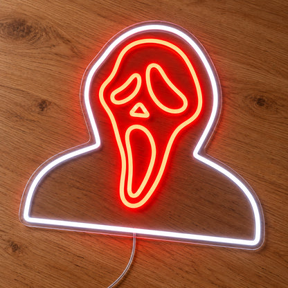 Hooded Ghostface Neon Sign featuring an orange Ghostface mask framed by a white hood and shoulder outline, illuminated on clear acrylic lying on a natural oak wooden surface.