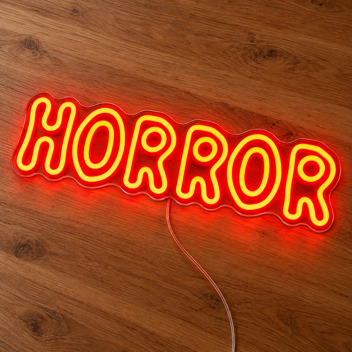 Horror Rounded Letters Neon Sign featuring the word Horror in rounded orange outline letters, illuminated on clear acrylic lying on a natural oak wooden surface.