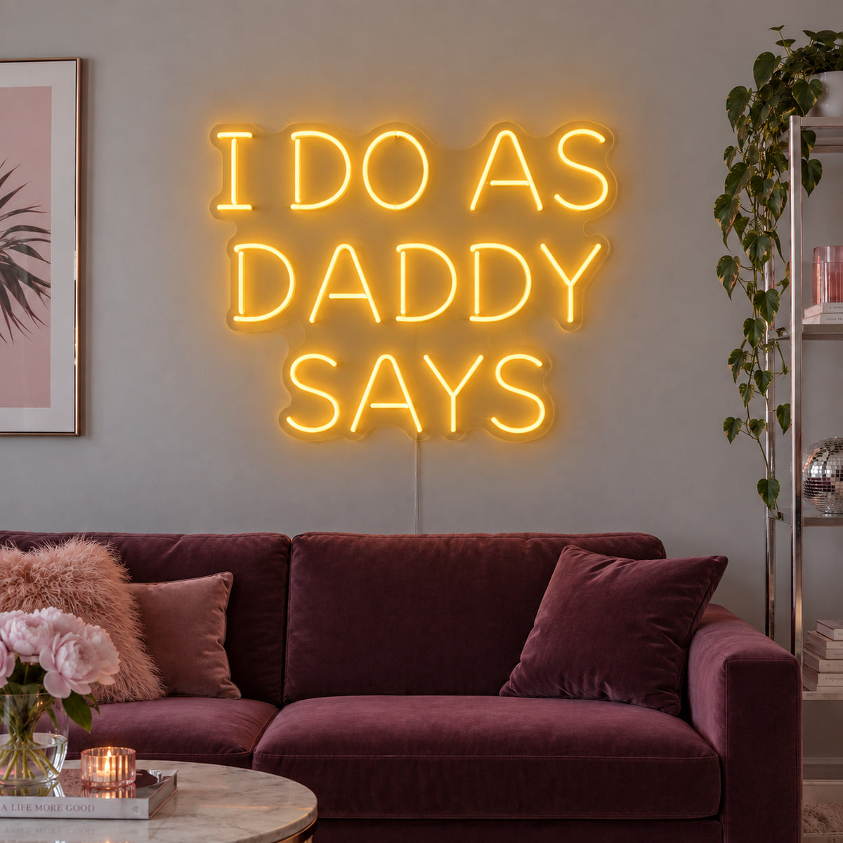 I Do As Daddy Says Neon Sign glowing gold above a burgundy sofa.