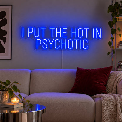 I Put The Hot In Psychotic Neon Sign glowing blue above a neutral sofa.