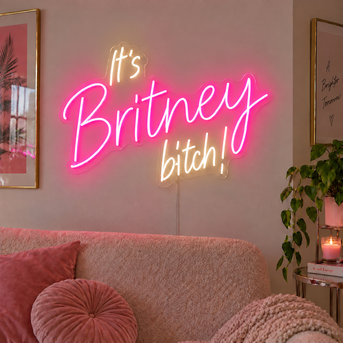 It's Britney Bitch Neon Sign with pink Britney script and warm white lettering in three lines on transparent acrylic, displayed on a living room wall