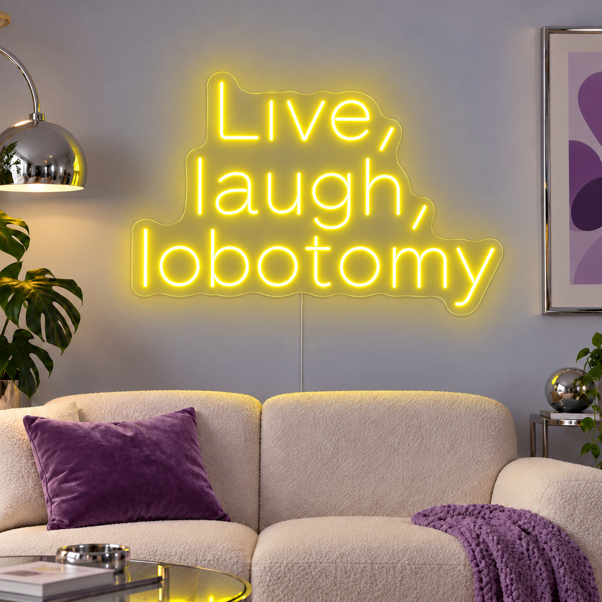Live, Laugh, Lobotomy Neon Sign with yellow lighting, displayed above a cream sofa with purple cushions.