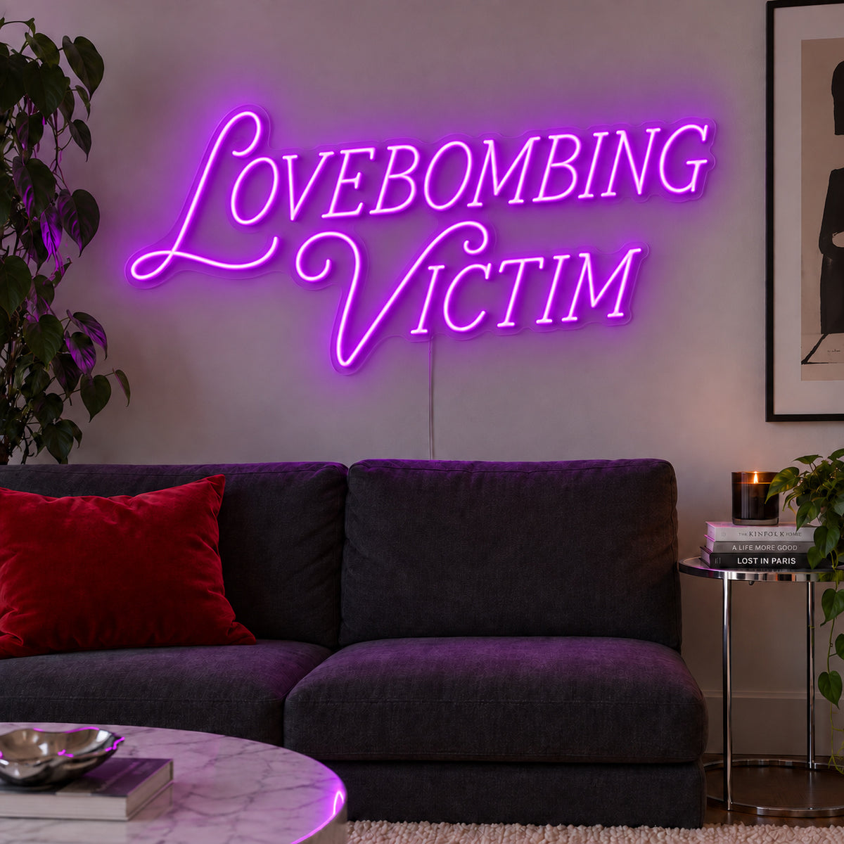 Lovebombing Victim Neon Sign with purple lighting, displayed above a dark sofa with red cushions.