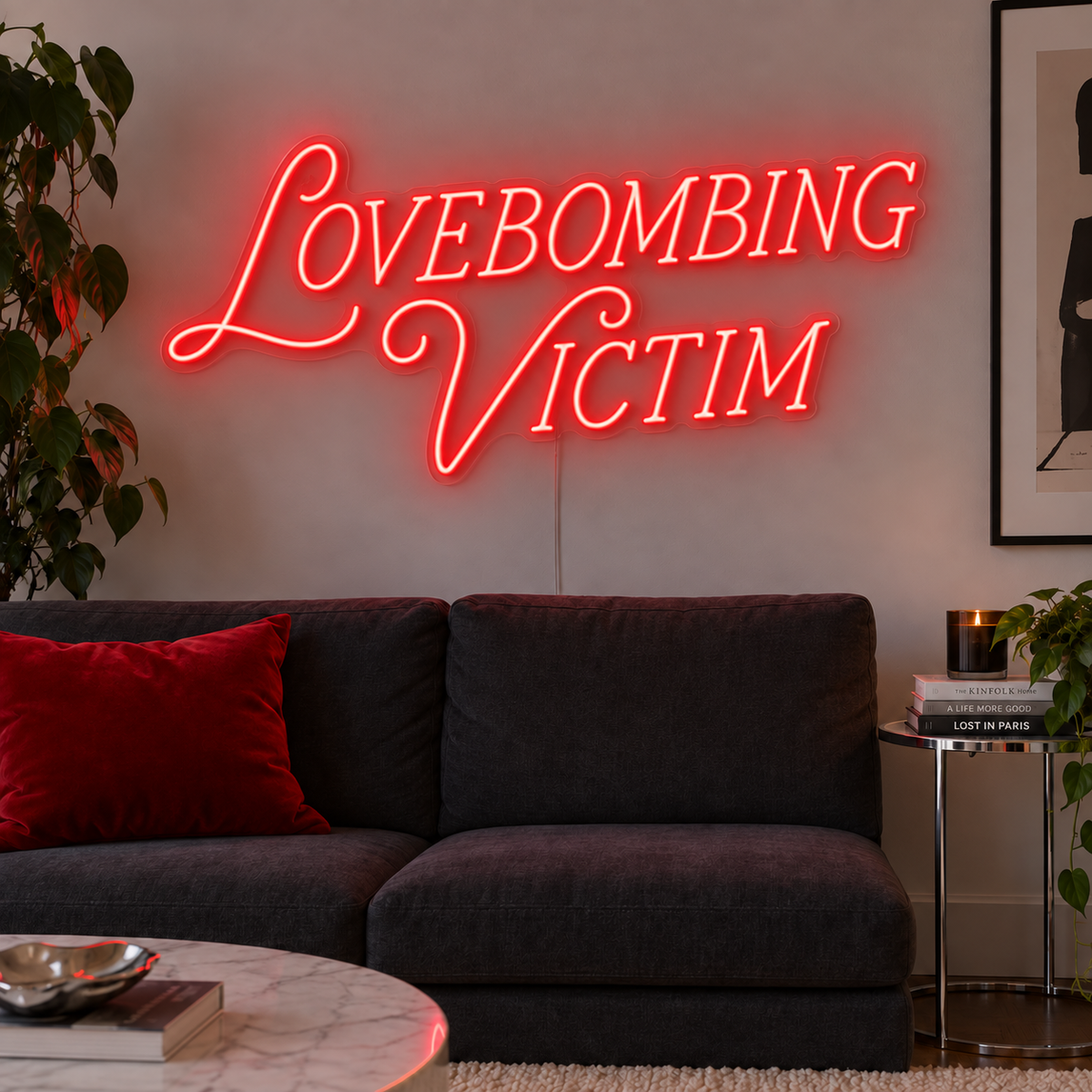 Lovebombing Victim Neon Sign in red above a dark sofa with red cushions.