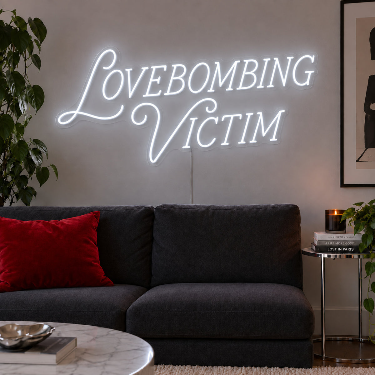 Lovebombing Victim Neon Sign, RGB colour-changing option shown in white above a dark sofa with red cushions.