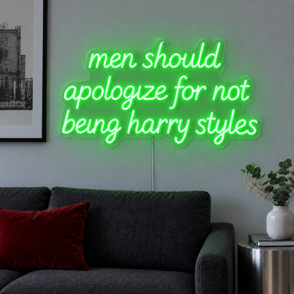 Men Should Apologize For Not Being Harry Styles Neon Sign with green lighting, displayed above a dark sofa.