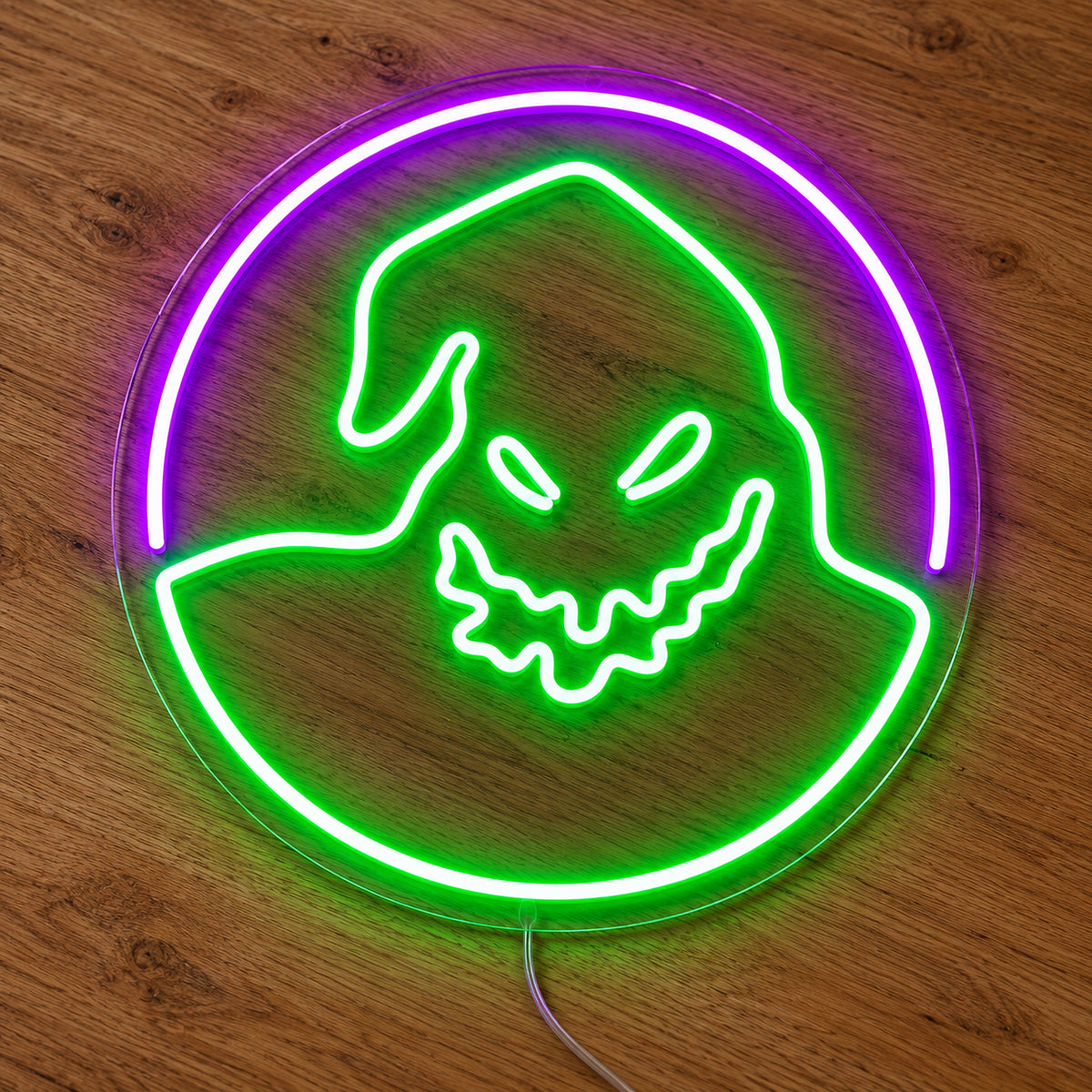 Oogie Boogie Neon Sign featuring Oogie Boogie's green face inside a circular outline with a purple upper arc, illuminated on clear acrylic lying on a natural oak wooden surface.