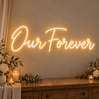 Our Forever Neon Sign on clear cut-to-shape acrylic, illuminated on a wall in a styled celebration setting