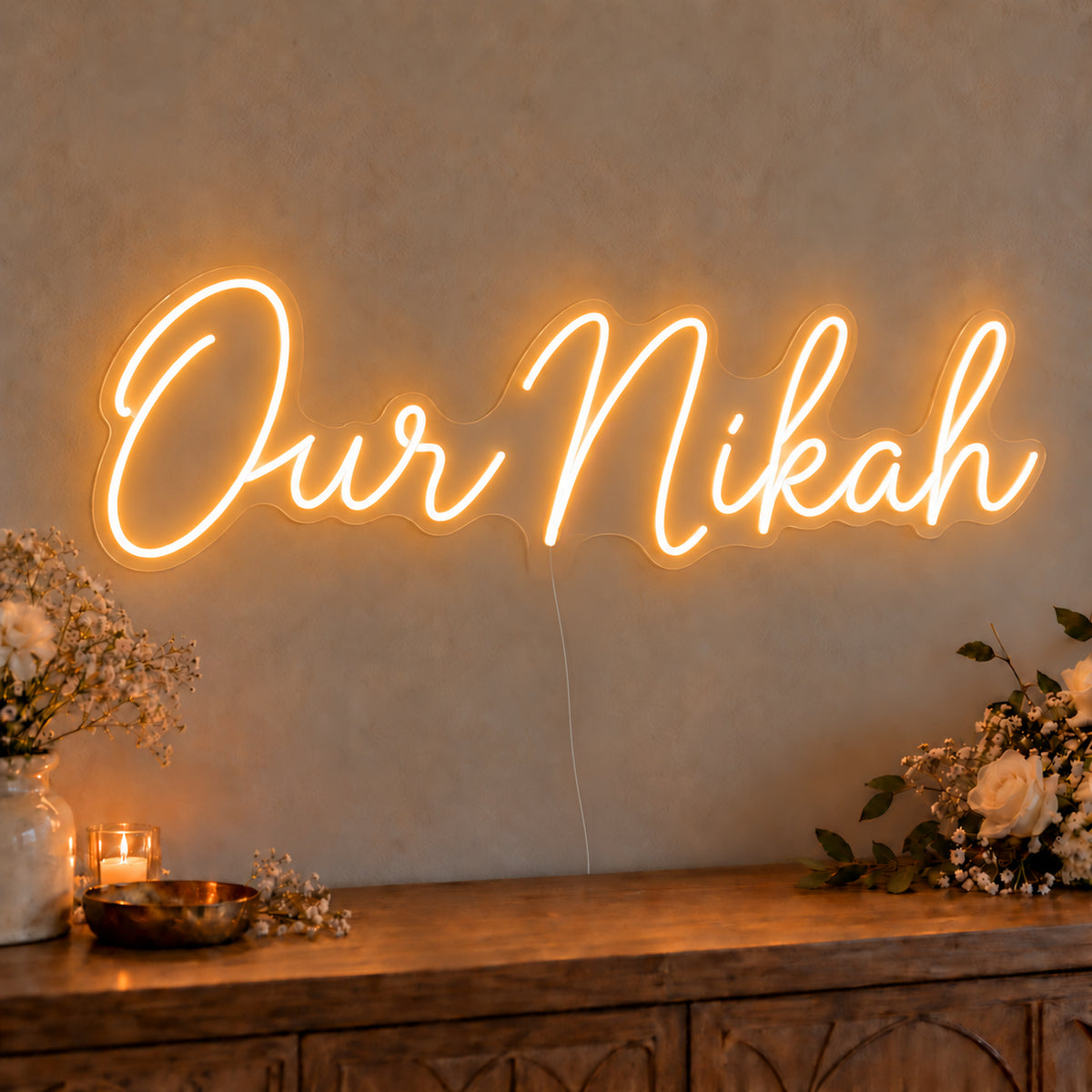Our Nikah Neon Sign on clear cut-to-shape acrylic, illuminated on a wall in a styled celebration setting