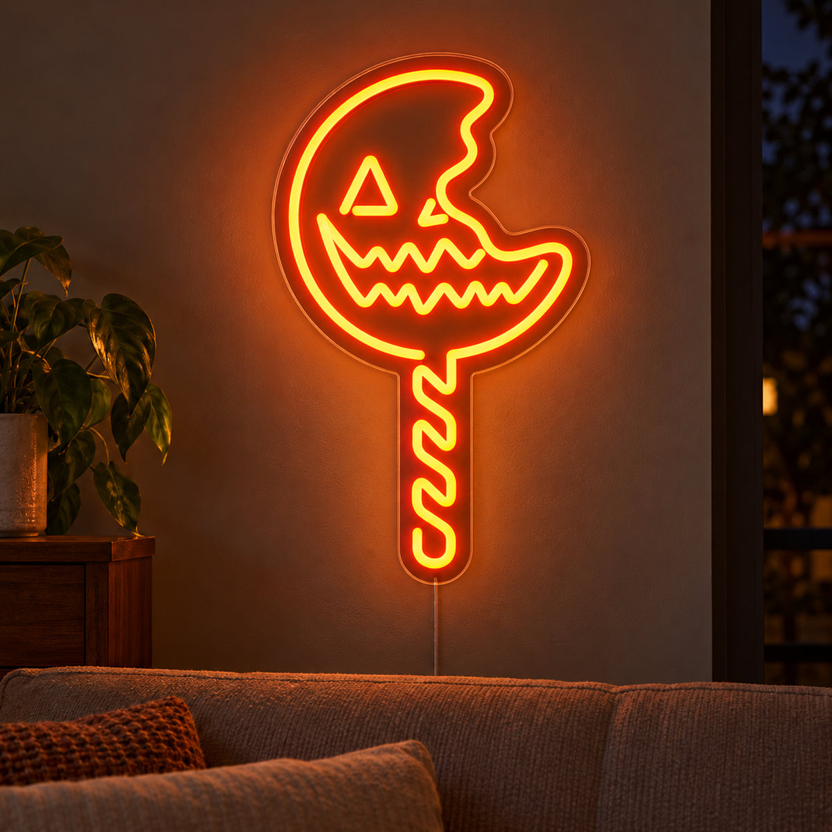 Pumpkin Lollipop Neon Sign featuring an orange jack o lantern lollipop with a bite shaped edge and a striped stick, glowing on a dark living room wall.