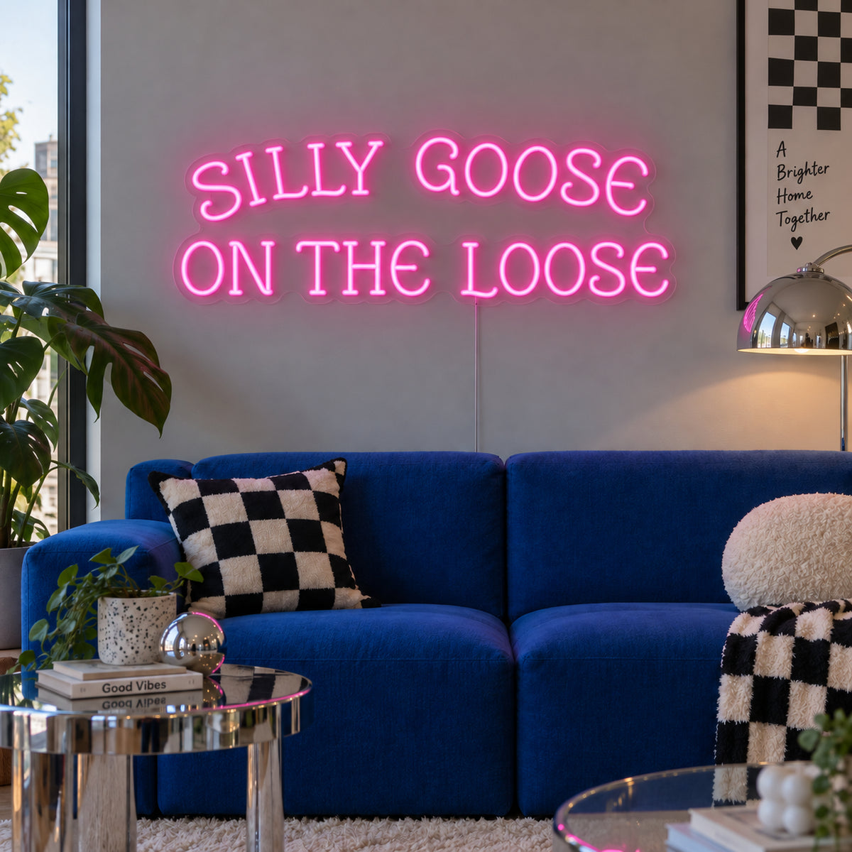 Silly Goose On The Loose Neon Sign in pink above a blue sofa with checkered cushions.