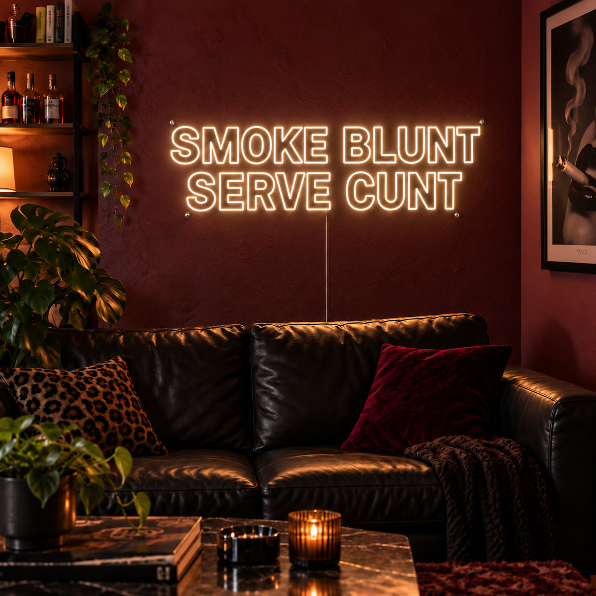 Warm White version of the Smoke Blunt Serve Cunt Neon Sign, shown above a black leather sofa.