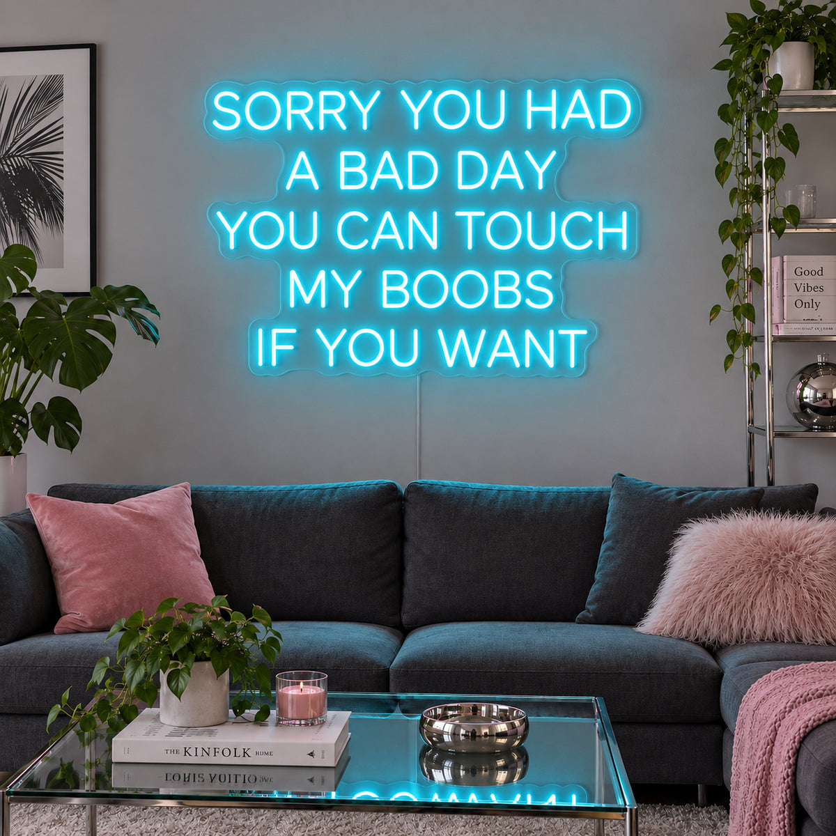 Ice Blue version of the Sorry You Had A Bad Day You Can Touch My Boobs If You Want Neon Sign, shown above a grey sofa with pink cushions.