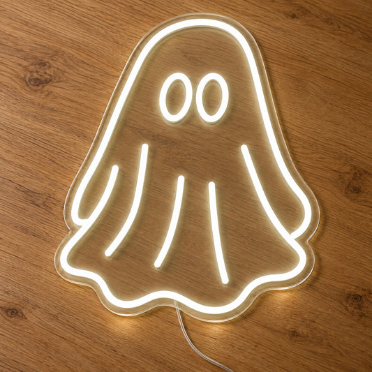 White Ghost Neon Sign featuring a white ghost outline with two oval eyes and a flowing sheet shaped body, illuminated on clear acrylic lying on a natural oak wooden surface.