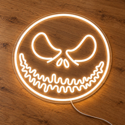 White Jack Skellington Face Neon Sign featuring Jack Skellington's eyes and stitched smile within a white circular face outline, illuminated on clear acrylic lying on a natural oak wooden surface.